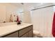 Modern bathroom showcasing a quartz countertop, gray cabinets, and a shower with white curtain at 10136 Worchester St, Commerce City, CO 80022