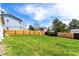 Large, grassy backyard with a wood fence, mature trees, and blue sky in the background at 10720 Moore Cir, Westminster, CO 80021