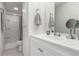 A bright bathroom with a white vanity, mirror, and a tiled shower with glass shelves at 10720 Moore Cir, Westminster, CO 80021