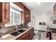 Cozy kitchen with dark wood cabinets, granite countertops, and a stainless steel sink offering natural light from the window at 10720 Moore Cir, Westminster, CO 80021