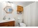 Traditional bathroom features hexagon mirror, oak vanity, and shower with white curtain at 32392 Lodgepole Dr, Evergreen, CO 80439