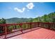A red wooden deck features mountain views under a sunny sky, inviting relaxation and scenic appreciation at 32392 Lodgepole Dr, Evergreen, CO 80439