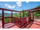 Red wooden deck with views of treed mountains and a bright blue sky with fluffy white clouds at 32392 Lodgepole Dr, Evergreen, CO 80439
