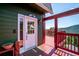 Front door leading to a red deck with scenic mountain views in background, accented with a rustic bear carving at 32392 Lodgepole Dr, Evergreen, CO 80439