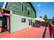 Exterior shot of a green home featuring a spacious wooden deck, seating, and an umbrella for outdoor enjoyment at 32392 Lodgepole Dr, Evergreen, CO 80439