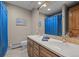 Bathroom featuring double sinks, wood cabinets, and a large mirror, plus view of shower with blue curtain at 3980 S Dexter St, Cherry Hills Village, CO 80113