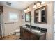 Bathroom with double sinks, dark cabinets, a window, tiled floors, and dark framed mirrors at 3488 Dawson Rd, Sedalia, CO 80135