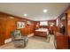 Cozy carpeted bedroom features warm wood paneling, a plush chair, and a comfortable queen-size bed at 3488 Dawson Rd, Sedalia, CO 80135