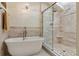 This bright bathroom includes a soaking tub, glass enclosed shower, and neutral tile throughout at 5149 E Links Cir, Centennial, CO 80122