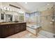 A well-lit bathroom featuring a granite-top double vanity, soaking tub, and glass enclosed shower at 9882 S Hoyt Ct, Littleton, CO 80127