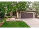 Charming home featuring a stone facade, covered porch, well-manicured lawn, and an attached two-car garage at 9882 S Hoyt Ct, Littleton, CO 80127
