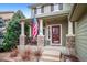 Cozy front porch with stone pillars, railings, and American flag at 9882 S Hoyt Ct, Littleton, CO 80127