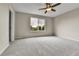 Bedroom features neutral carpet, a ceiling fan and a large window overlooking trees at 22974 E Dorado Dr, Aurora, CO 80015