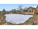 Backyard featuring a snow-covered lawn with manicured landscaping and mature trees at 15855 Wild Horse Dr, Broomfield, CO 80023