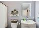 Bathroom featuring a sleek mirror, modern sink, toilet, and organized open shelving at 1629 Valentia St, Denver, CO 80220