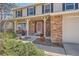 Inviting covered porch with white columns, brick accents, and landscaped garden at 1376 S Laredo Ct, Aurora, CO 80017