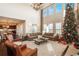 Bright living room with a tall Christmas tree, fireplace, large windows, and comfortable, neutral-toned furnishings at 22435 Boundstone Dr, Parker, CO 80138