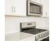 Close-up of stainless steel range and microwave with bright white cabinets and quartz countertops at 1935 Coolidge Way, Aurora, CO 80018