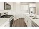 Bright kitchen features stainless steel appliances, white cabinets, island, and wood-look floors at 1935 Coolidge Way, Aurora, CO 80018