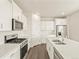 Bright white kitchen features stainless steel appliances, gray backsplash, and a central island with a double sink at 1935 Coolidge Way, Aurora, CO 80018