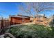 Fenced backyard with wooden storage building, grass, stone walkway, and wooden deck with table and chairs at 241 N Grant St, Denver, CO 80203