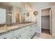 Bathroom featuring dual sinks, granite countertops, white cabinetry, and decorative wall art at 15530 W 64Th Pl # C, Arvada, CO 80007