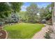 Manicured backyard with flowerbeds, mature trees, and brick-paved pathway at 11237 W Ford Dr, Lakewood, CO 80226