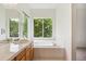 Bright bathroom featuring a soaking tub with a view of lush greenery and tile flooring at 11237 W Ford Dr, Lakewood, CO 80226