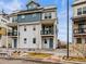 Charming three-story townhome featuring a blue door, small patio, and well-maintained landscaping at 6162 W 28Th Ct, Wheat Ridge, CO 80214