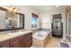 Luxurious bathroom featuring a soaking tub with tile surround and a large vanity with dark wood cabinets at 7172 S Oakleaf St, Bennett, CO 80102