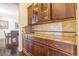 Close-up of a butler's pantry featuring granite countertops, tile backsplash, and dark wood cabinets at 7172 S Oakleaf St, Bennett, CO 80102
