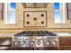 Close up of gas range with decorative tile backsplash and stainless steel range hood, perfect for gourmet cooking at 7172 S Oakleaf St, Bennett, CO 80102