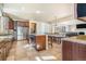 Open concept kitchen featuring a large island with bar seating, stainless appliances, and tile flooring at 7172 S Oakleaf St, Bennett, CO 80102