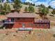 Exterior view of home with a deck, brick retaining wall, and grassy yard at 24170 Matterhorn Dr, Indian Hills, CO 80454