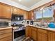 Compact kitchen featuring wood cabinets, stainless appliances, and mountain views at 24170 Matterhorn Dr, Indian Hills, CO 80454