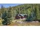 Beautiful exterior view of the red home surrounded by pine trees and flowing river at 189 Ginger Quill Ln, Breckenridge, CO 80424