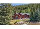 A picturesque exterior view of the red home nestled amongst lush greenery and a flowing river at 189 Ginger Quill Ln, Breckenridge, CO 80424