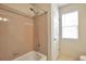 Simple bathroom with combination tub and shower, beige tiling, and window at 18852 E Progress Ave, Centennial, CO 80015