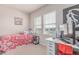 A bright bedroom with carpet, windows, a desk, and a bed with a colorful comforter and stuffed animals at 24043 E Florida Ave, Aurora, CO 80018