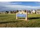 Picturesque community park with a welcoming sign, open green space, and beautiful homes in the background at 24043 E Florida Ave, Aurora, CO 80018