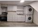 Basement kitchen featuring modern appliances, white cabinetry and stacked washer/dryer at 1977 S Yates S St, Denver, CO 80219