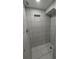 Updated bathroom shower with gray-tiled walls and floors and a recessed shelf at 1977 S Yates S St, Denver, CO 80219