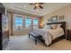 Spacious main bedroom featuring a tray ceiling, large windows, neutral carpet, and a decorative ceiling fan at 10646 Winding Pine Pt, Highlands Ranch, CO 80126