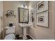 Powder room features a pedestal sink, framed mirror, elegant light fixture, and stylish decor at 10646 Winding Pine Pt, Highlands Ranch, CO 80126