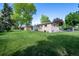 Expansive backyard features lush lawn and mature trees surrounding a brick home at 12162 W Dakota Dr, Lakewood, CO 80228