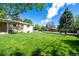 View of spacious, grassy backyard and side of brick home under a bright blue sky at 12162 W Dakota Dr, Lakewood, CO 80228