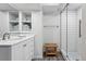 Bright bathroom boasts a white vanity, open shelving with neatly stacked towels, and a modern glass-enclosed shower at 5441 S Dayton Ct, Greenwood Village, CO 80111