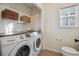 Convenient laundry room features a washer and dryer, storage shelves, and a bright window at 4526 Lyndenwood Pt, Highlands Ranch, CO 80130