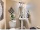 Cozy powder room with pedestal sink, decorative mirror, and modern lighting at 301 Harvest St, Longmont, CO 80501