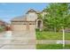 Charming two-story home with a stone and tan siding, three-car garage, and a well-maintained lawn at 594 Fall River Ct, Brighton, CO 80601